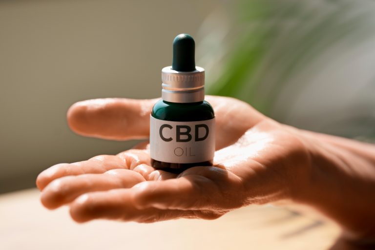 Hand holding a bottle of CBD oil for wellness use